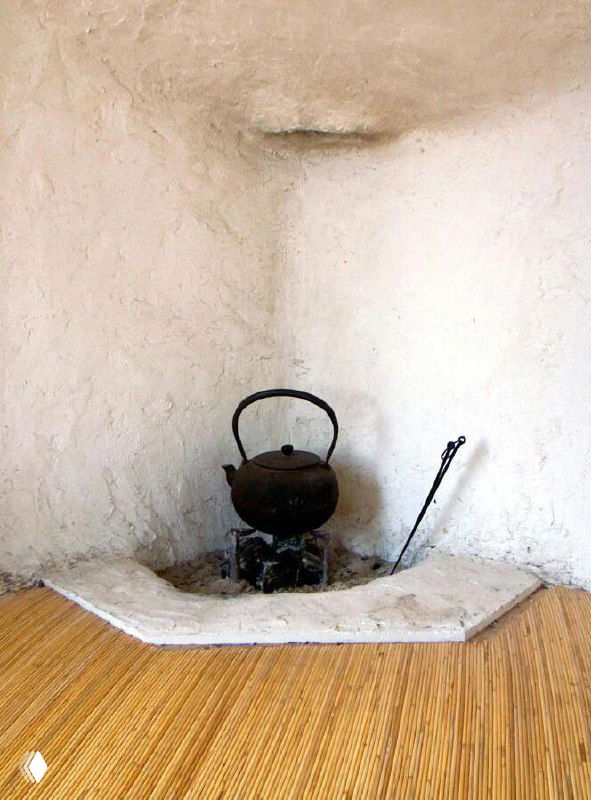 Интерьерный кадр: очаг и чайник в нише из белой глины, плетёный пол, традиционная японская атмосфера чайной комнаты.