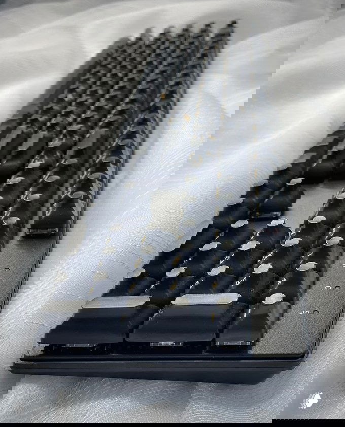 Боковой ракурс прототипа клавиатуры DeLiz с волнообразными углублёнными клавишами на фоне ткани, видно колпачки.