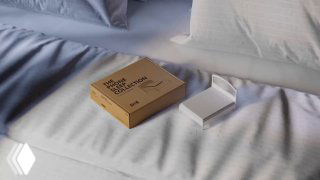 Крупный план коробки «The Phone Sleep Collection» и мини-кроватки для смартфона на постели — упаковка и модель в интерьерной ночной сцене.