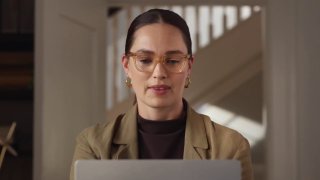 Женщина в очках смотрит на экран ноутбука — рекламный/презентационный кадр, иллюстрирующий работу персонального ассистента на устройстве.