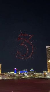 В небе над Лас-Вегасом дроны выстроились в цифру «3» — кадр выступления, на переднем плане городской пейзаж и автомобили.