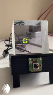 Демонстрационный прибор: прозрачная призма (пирамида) над платой с камерой и проводами, на которой показывается управляемая голограмма.