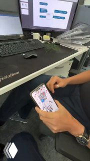 Руки человека с смартфоном над рабочим столом: видны экран с приложением, клавиатура и запястье — иллюстрация вшитого NFC‑чипа.