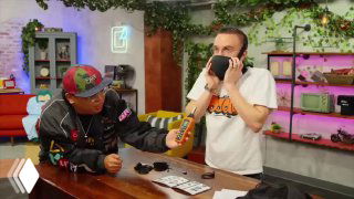 Ведущий в студии примеряет звукоизолирующую маску Vekta, рядом у второго человека виден направленный микрофон и реквизит передачи.