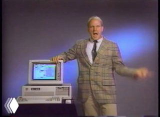 Ретро-кадр: мужчина в пиджаке рядом со старым персональным компьютером, на экране виден графический интерфейс ранней Windows.