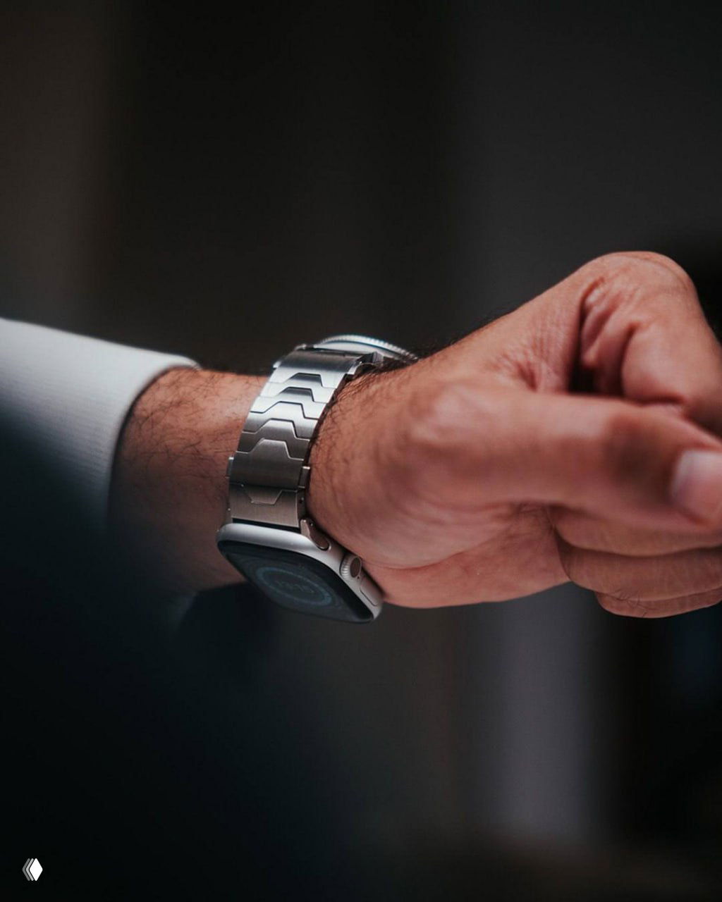 Запястье мужчины в деловом костюме: стальной браслет Smartlet One с установленными классическими часами поверх смарт‑часов, вид сбоку