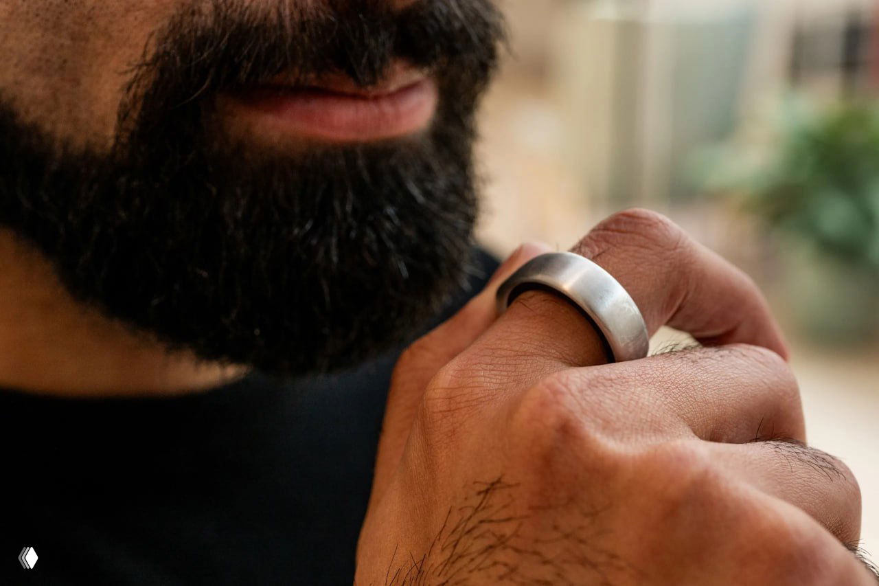 Мужчина с бородой прикасается к кольцу на пальце, демонстрируя управление и взаимодействие пользователя с гаджетом.