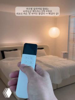 Рука держит пульт управления на фоне спальни с раздельной кроватью — двуспальное ложе частично раздвинуто на две односпальные, мягкое освещение и минималистичный интерьер.