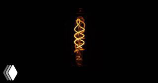 Фотография лампы с витой нитью накаливания на тёмном фоне, визуальная метафора идей, инноваций и технологических открытий Kosmos в этой публикации.