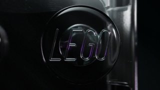 Крупный план фирменного логотипа LEGO на тёмном фоне, подчёркивающий бренд и анонс новой умной детали Smart Brick для наборов.