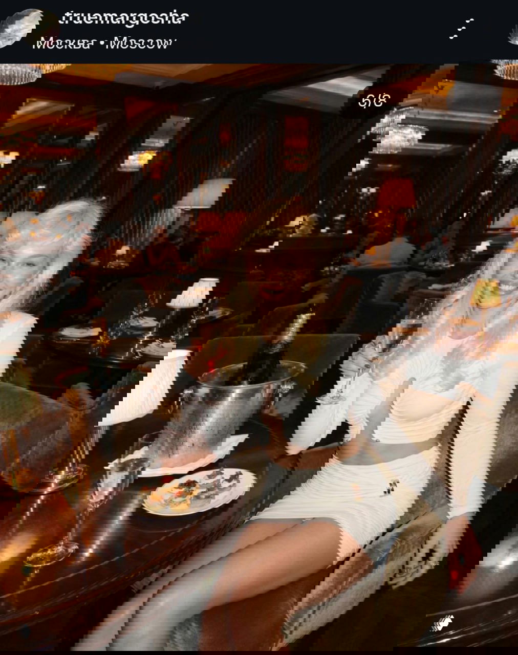 Девушка в ресторане с бокалом шампанского и закусками; образ «Маргоша» на рекламной фотосессии, демонстрирующий коммерческое использование аккаунта.