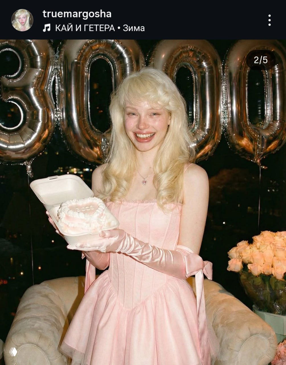 Девушка в розовом платье держит торт в коробке; кадр с вечеринки аккаунта, демонстрация визуального контента, используемого для продвижения виртуальной персоны.