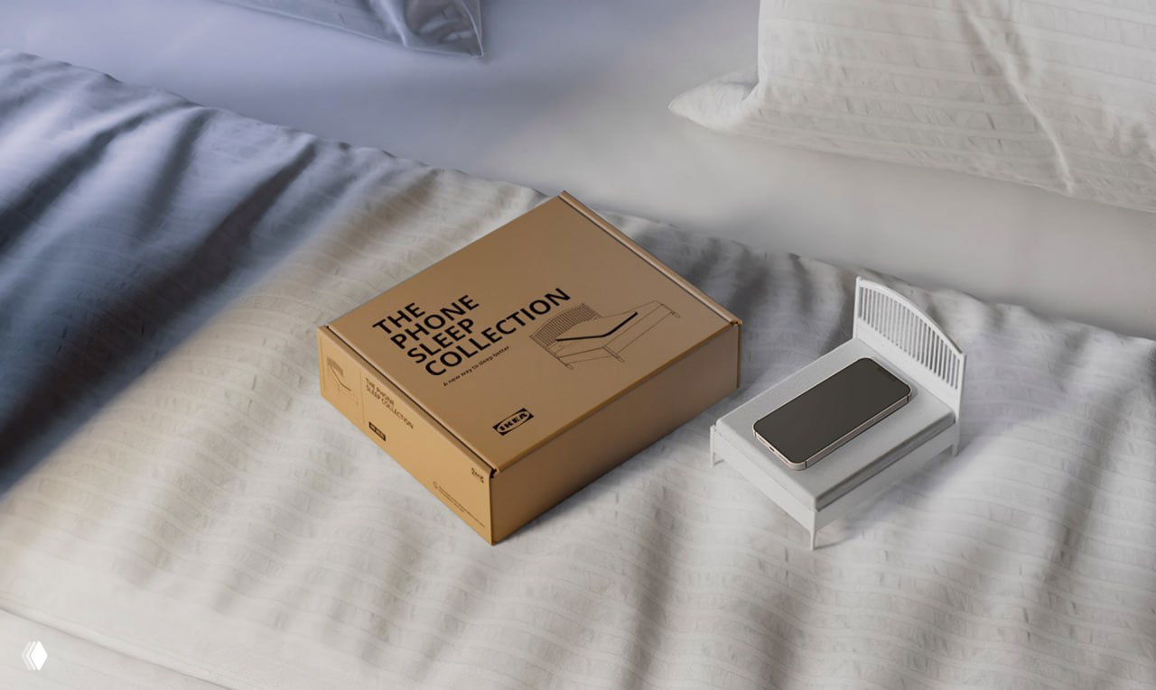 Мини-кроватка и упаковочная коробка «The Phone Sleep Collection» на кровати, телефон лежит в кроватке — рекламный ракурс продукта IKEA.
