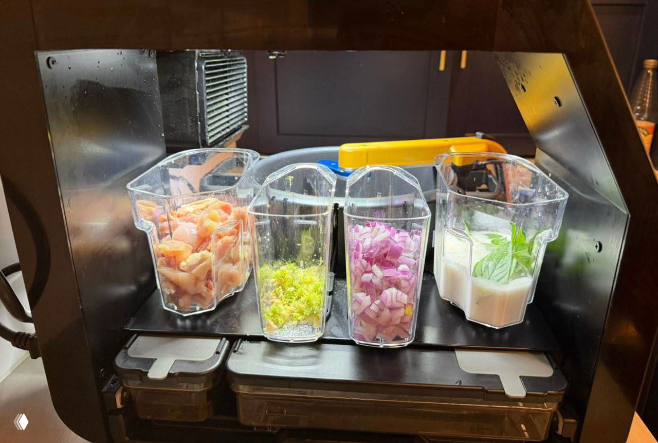 Внутренний отсек Posha с четырьмя прозрачными ёмкостями, наполненными курицей, зеленью, луком и соусом.