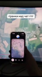 Руки держат смартфон, снимающий изображение на экране телевизора: видна карта и надпись «пранки над чат гпт», кадр в тёмной комнате.