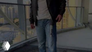 Человек держит самодельный «джедайский меч» на балконе: видна рукоять, прозрачная пружинящая трубка и светящаяся LED-лента, кадр из ролика.