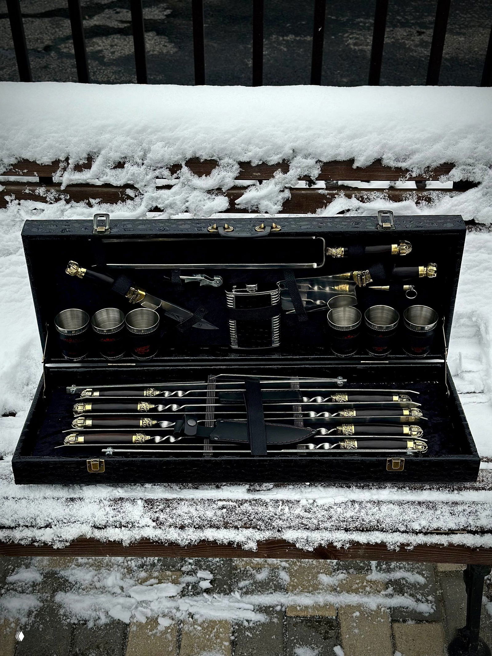 Открытый кейс с набором: ровно уложенные шампуры с витой сталью, кожаные фиксаторы и декоративные латунные навершия на ручках.