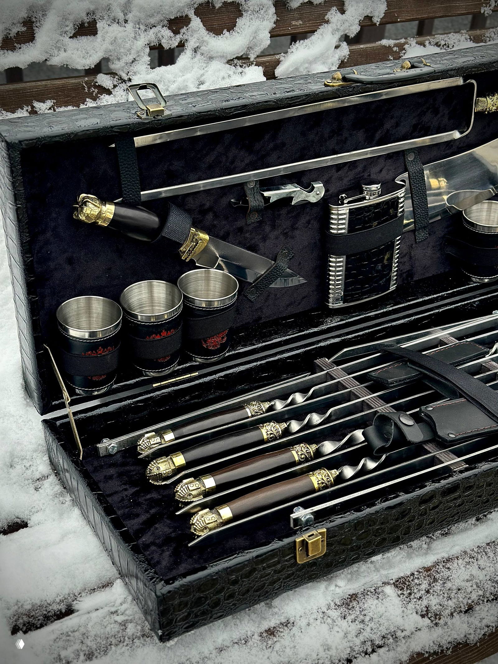 Крупный план зоны с чашками из нержавеющей стали, ножом и фляжкой — аксессуары крепятся к крышке кейса ремнями и люверсами.