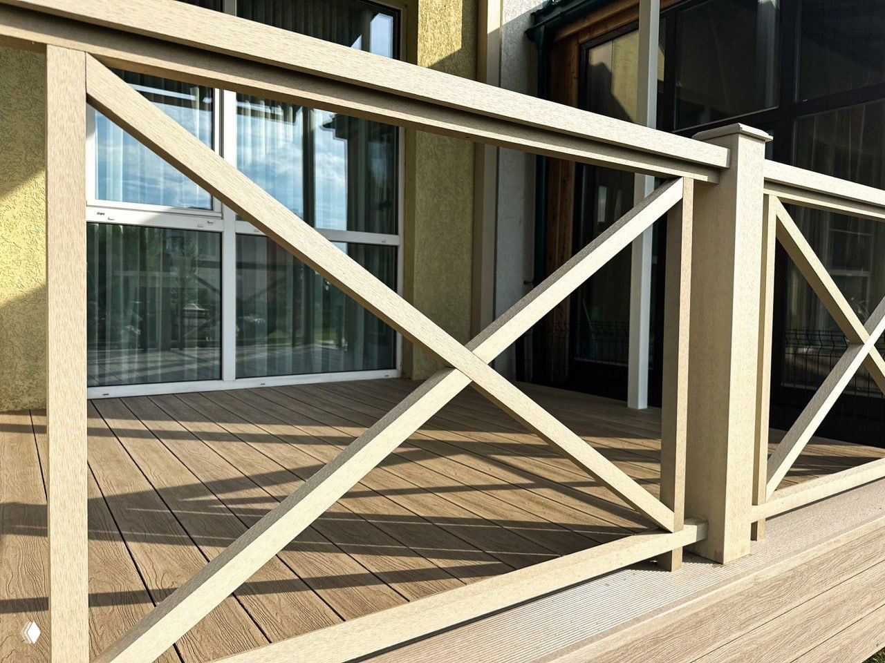 Крупный план перил и настила из ДПК: перекрёстные стойки ограждения и выраженная текстура доски при солнечном освещении.