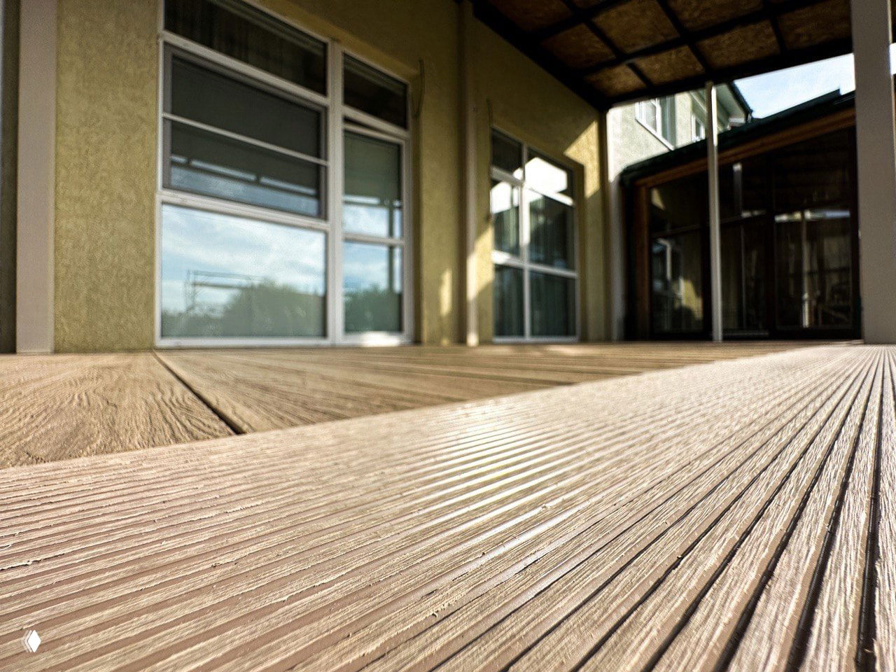 Макро-съёмка рифлёной поверхности декинга из ДПК: видна глубина тиснения, равномерная фактура и оттенок профиля рядом с домом.