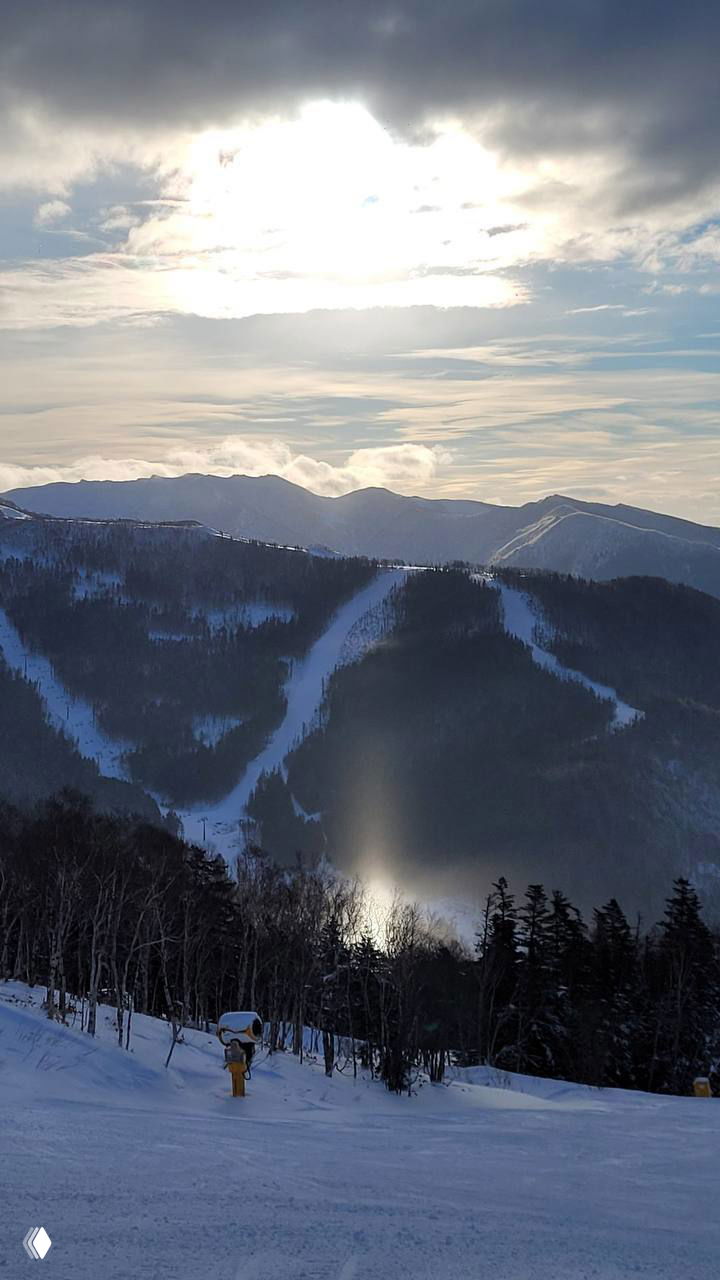 Дальний вид горной долины и яркий вертикальный солнечный столб, который отражается в снегу и среди леса на склоне Сахалина.