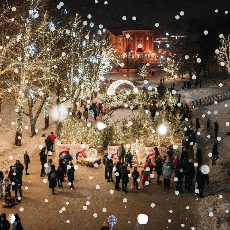 Рязанская праздничная ярмарка: люди гуляют по освещённой площади среди киосков и ёлок, вечерняя суета и огни.