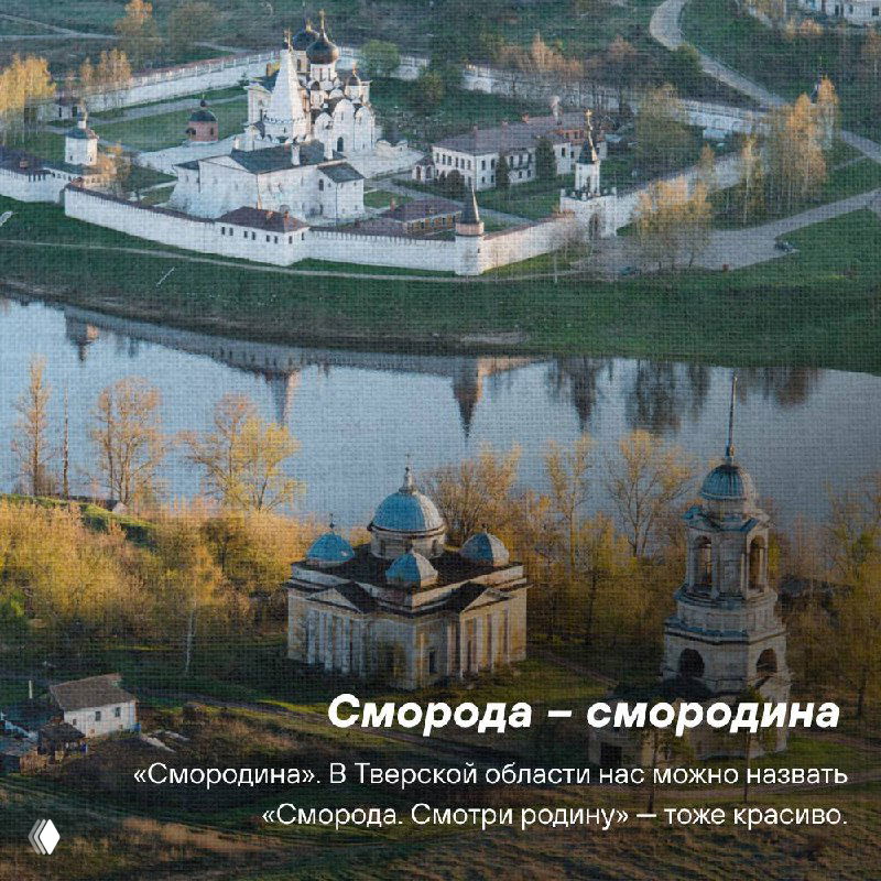 Аэросъёмка древнего поселка на берегу реки в Верховолжье: деревянные постройки, мост и осенние деревья в зеркале воды.