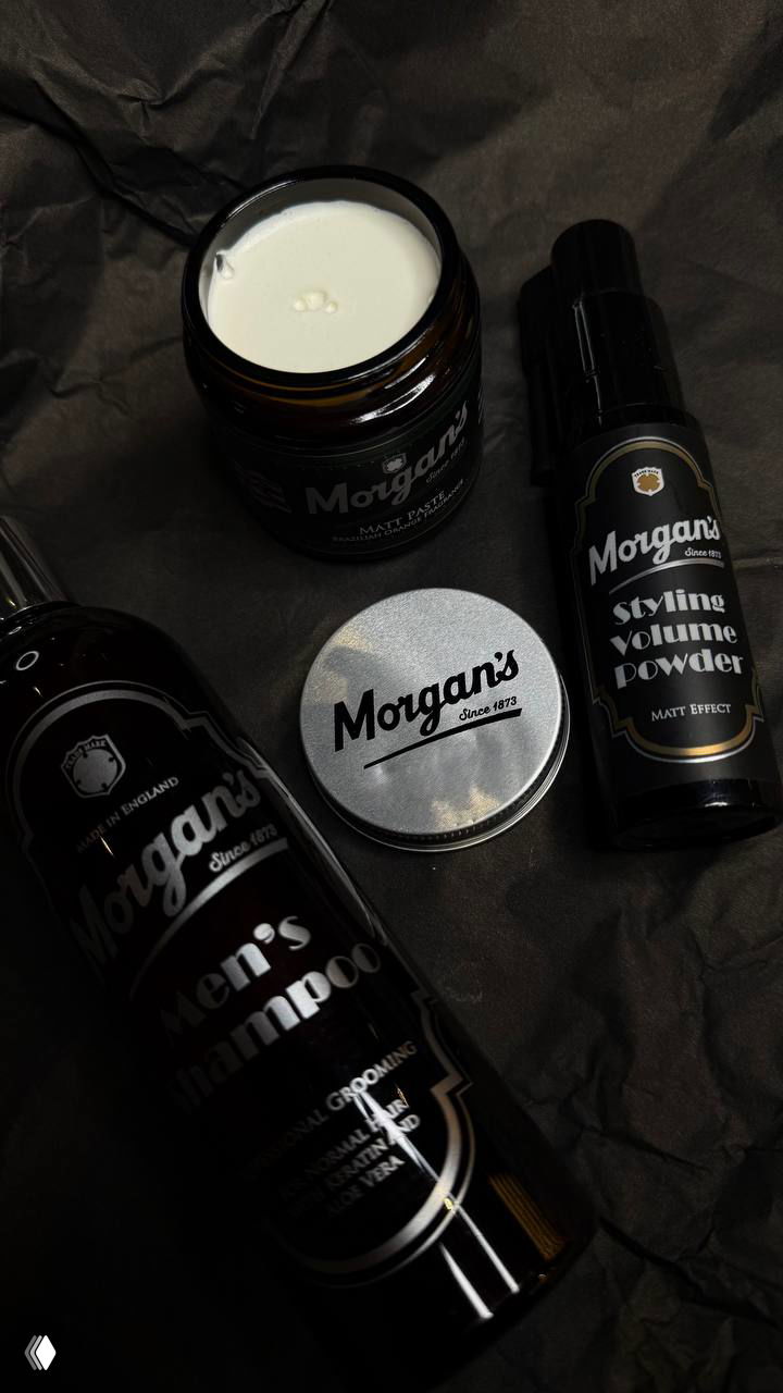 Компоновка косметики Morgans: шампунь, помада и стайлинговый порошок рядом с металлическими элементами в мужском наборе.