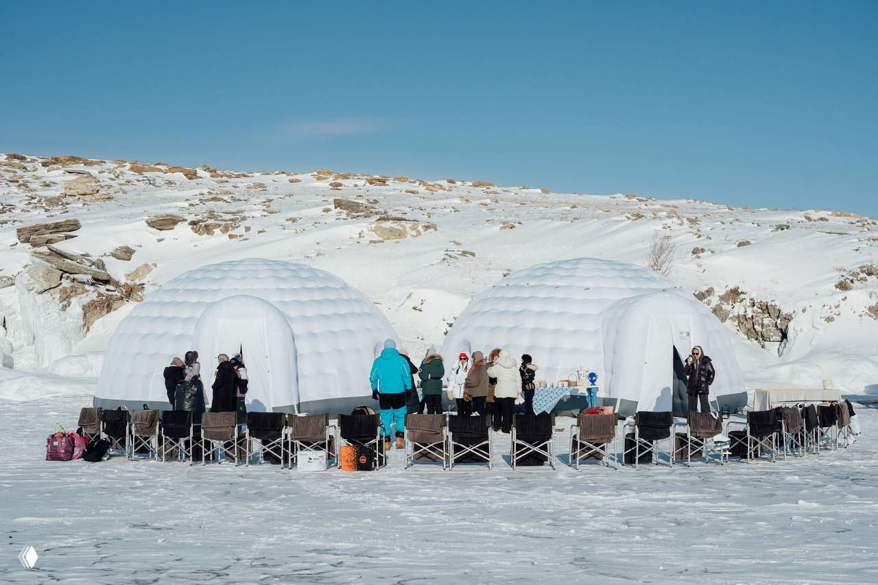 Надувные куполообразные юрты-иглу на льду Байкала и ряды стульев для участников — организованная площадка для разговоров и обедов на льду.