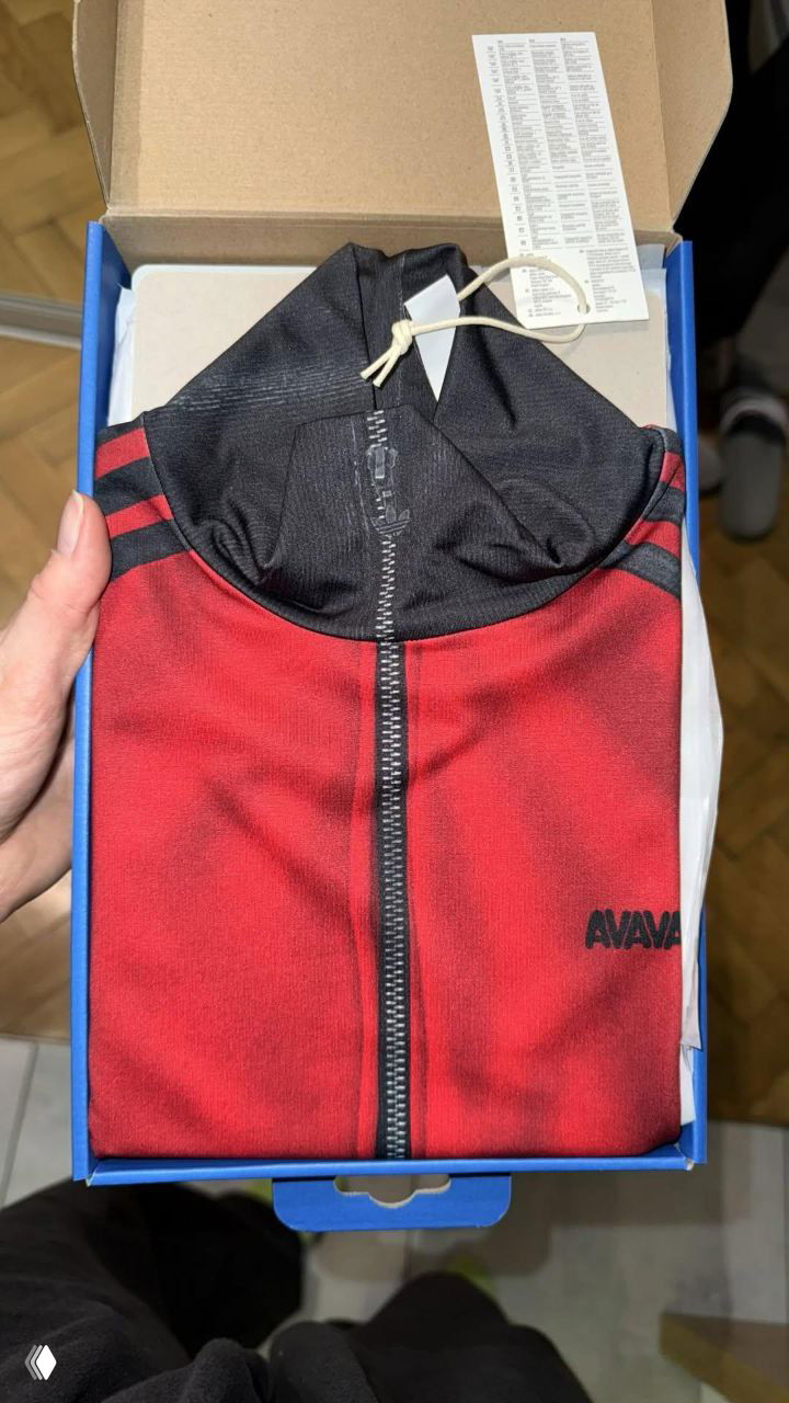 Открытая коробка с аккуратно сложенным красно‑чёрным спортивным топом AVAVAV и бумажной инструкцией/этикеткой — фото товара в упаковке.