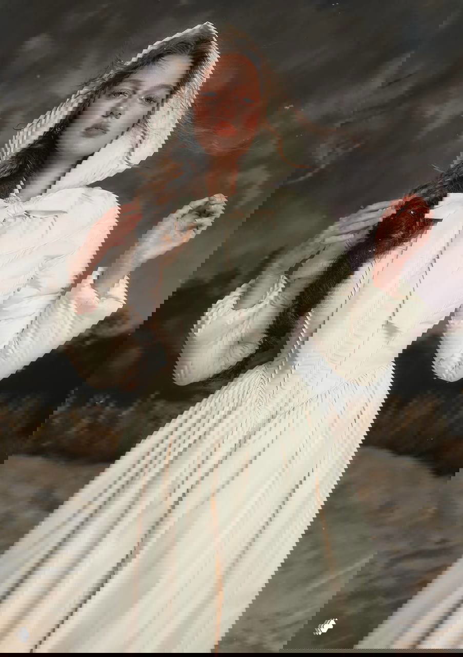 Модель в белом пуховике‑платье LaceMade с капюшоном и бантом, корсетный верх и романтический образ на нейтральном студийном фоне.