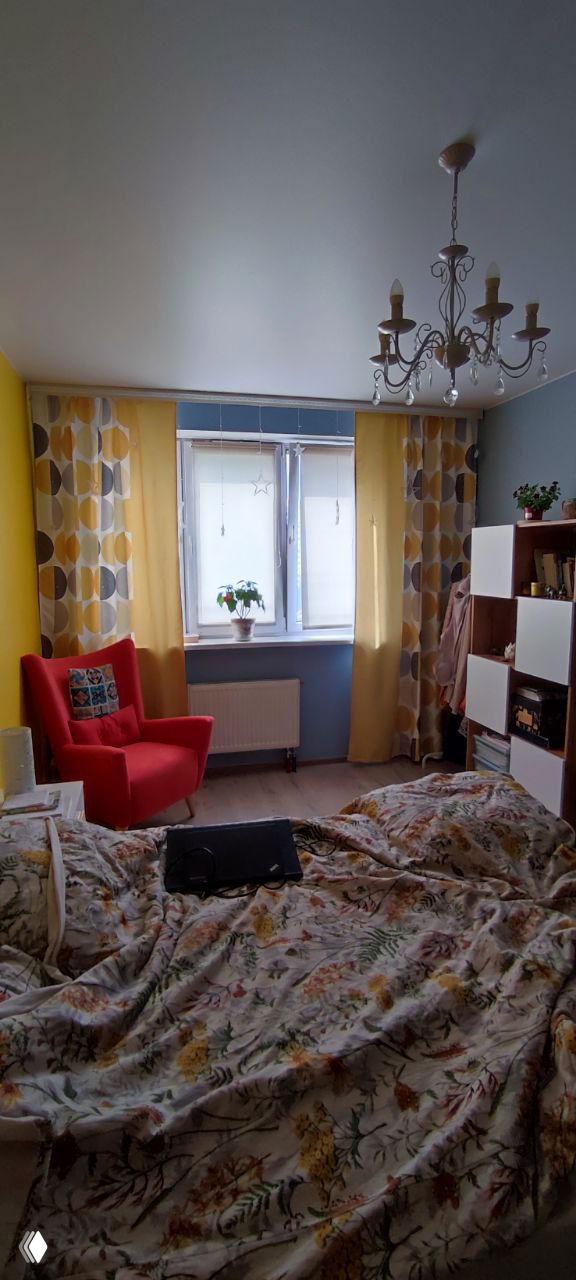 Светлая комната с желтой стеной, красным креслом, окном и кроватью; оформленный интерьер отражает приток энергии и изменения.