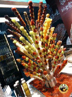 Пучок танхулу — карамелизированные фрукты на палочках на прилавке пекинского рынка, много разноцветных сладких сиропов и блеска.