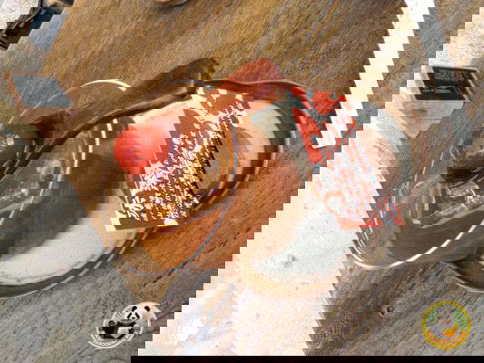 Стеклянная чашка с напитком и керамической ложкой, возможно яблочный кофе, поданная на столе с биркой и блюдцем в кафе Пекина.