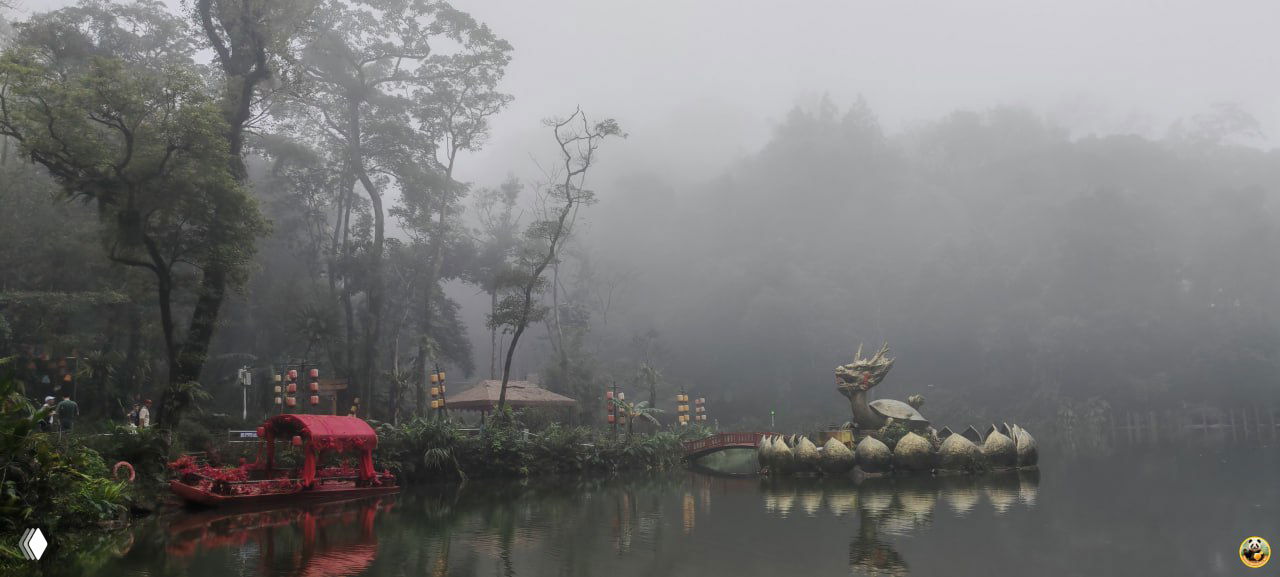 Панорамный вид на озеро парка Байхуань в густом тумане: береговая растительность, декоративные лодки и мистическая атмосфера.