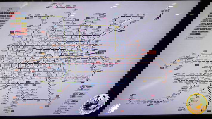 Схема пекинского метро — запутанная карта с множеством разноцветных линий и обозначениями станций и пересадок на стенде в вестибюле.