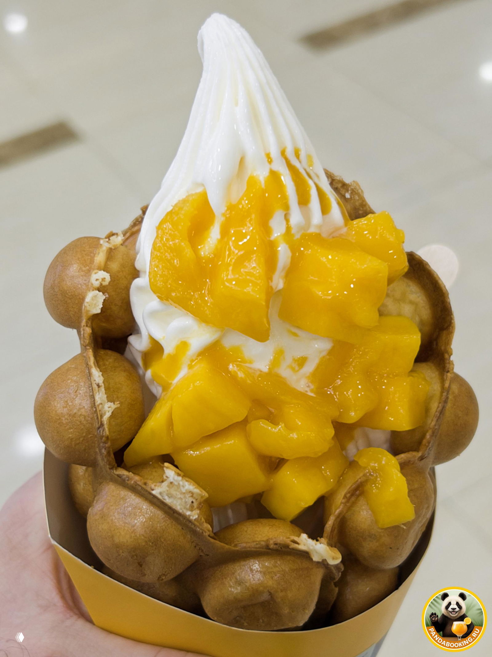 Крупный план вафельного мороженого с крупными кусочками спелого манго, видно кремовую текстуру и сочные кубики.