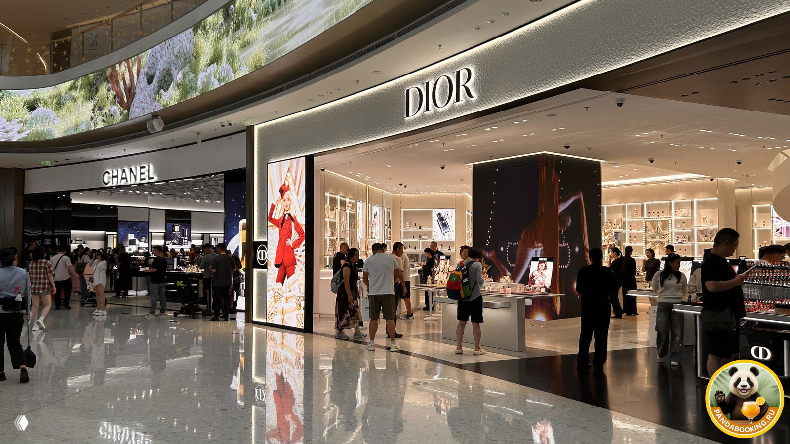 Большие корнеры Dior и Chanel в зоне парфюмерии и косметики: стойки с продуктами и посетители у витрин.