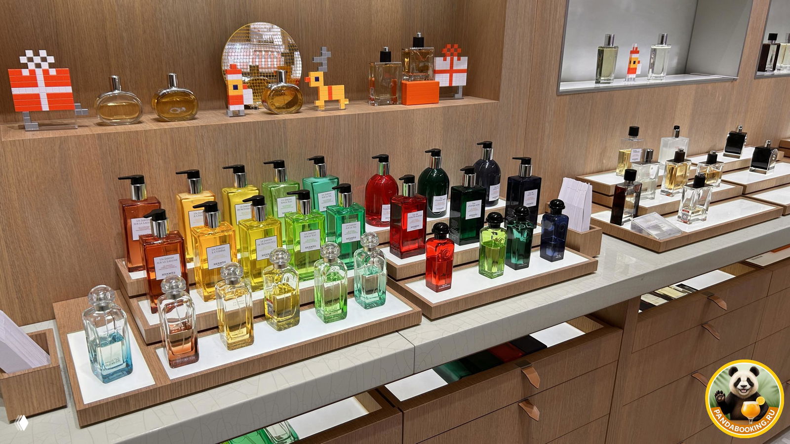 Ряд разноцветных флаконов парфюма на деревянных подставках: аккуратная экспозиция нишевых и дизайнерских ароматов.