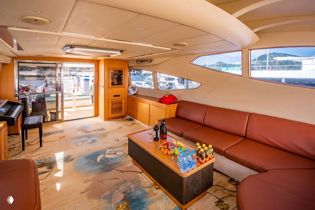 Интерьер прогулочной яхты: салон с кожаными диванами, столиком с фруктами и бутылками воды, большие окна и вид на причал