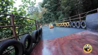 Кадр из ролика: водный аттракцион в парке Gulong в Гуанчжоу — пластиковая лодка в канале и защитные покрышки-ограждения по краям