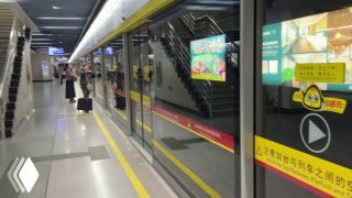 Платформа метро Гуанчжоу с защитными раздвижными дверями и стоящим поездом; видно табло и порядок на станции.