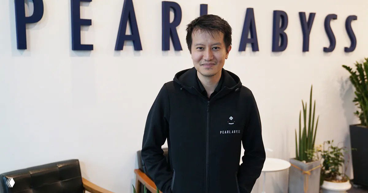 Мин Ле, один из создателей Counter-Strike, позирует в офисе на фоне крупного логотипа Pearl Abyss — иллюстрация к новости о его выступлении в Москве.