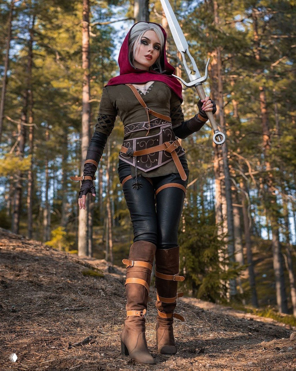 Илона Бугаева в косплее Цири: полный рост в лесу, кожаный корсет и сапоги, красный капюшон и длинный меч в руках