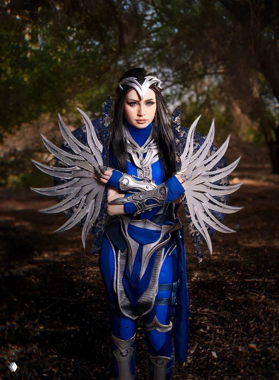 Косплей Китаны из Mortal Kombat 1 от Анны: полный сине‑серебристый костюм с декоративными лезвиями, модель позирует в лесном антураже.