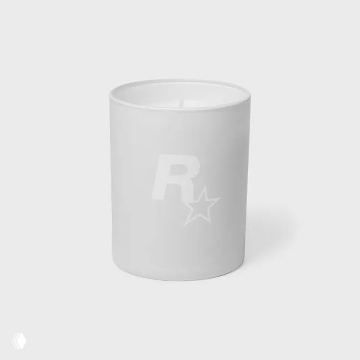 Фотография белой керамической свечи Vice Candle с логотипом Rockstar (буква R со звездой) на светлом нейтральном фоне, официальный товарный снимок.