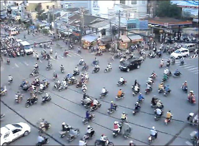 Вид перекрёстка с сотнями скутеров и мотоциклов, движение хаотичное — визуальная метафора женской многозадачности, стресса и влияния на ЖКТ