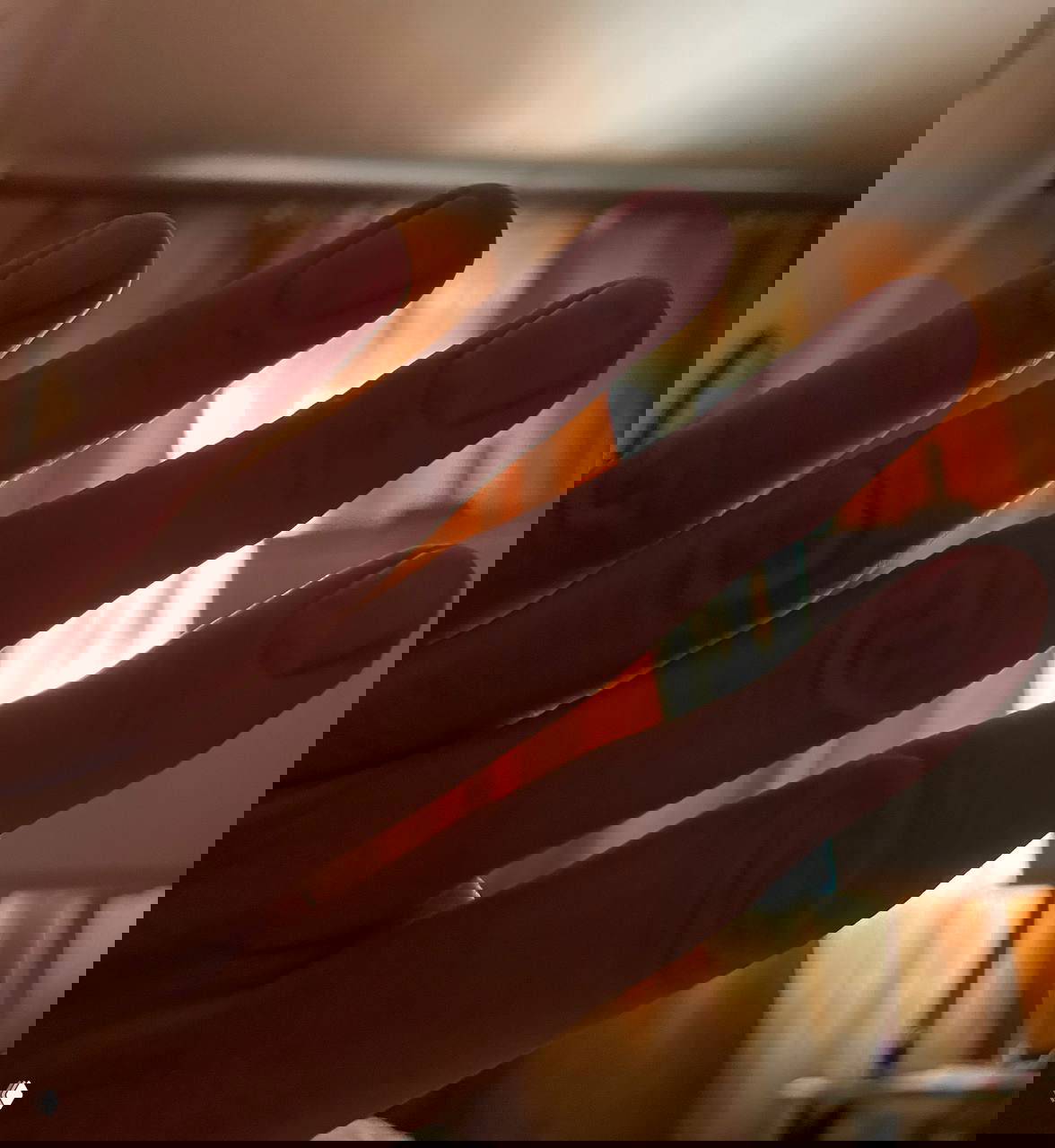 Крупный план женской руки с аккуратными ногтями и вытянутыми пальцами на фоне светлых занавесок и мягкого дневного света в комнате, домашняя сцена