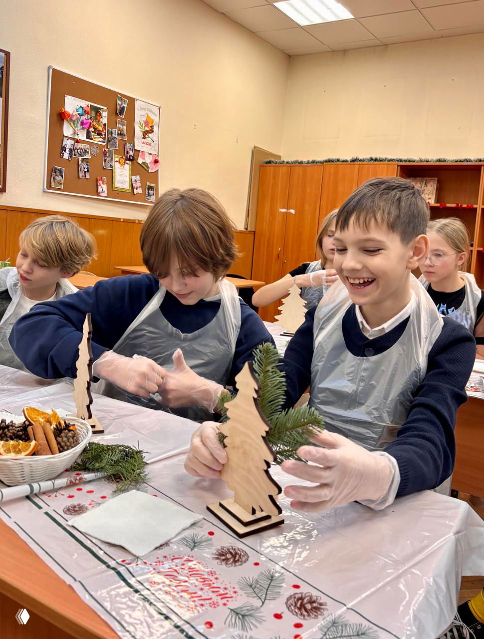 Хлопнувшие улыбки мальчиков за столом, они примеряют пластиковые перчатки и декорируют маленькие ёлочки.