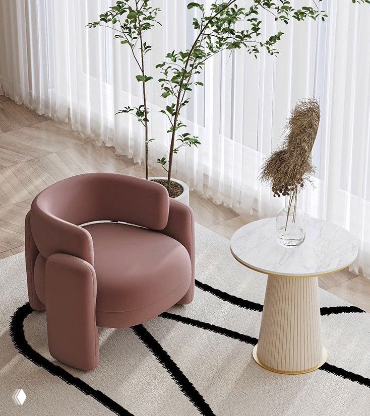 Розовое кресло с фланелевой обивкой и деревянной рамой в светлом интерьере с круглым столиком и растениями на фоне.